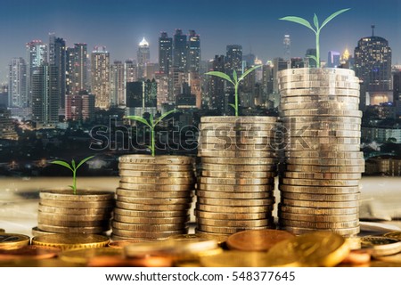 double exposure of golden coins stacks on table with tree growing on top and blur city night background, money and investment concept