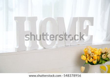 Wooden letters created in word Home against the window. Image for the background for the text.