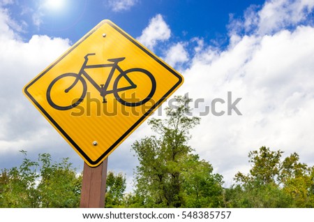 Yellow Traffic Sign Warning against Passing Bicycles. Lens Flare.