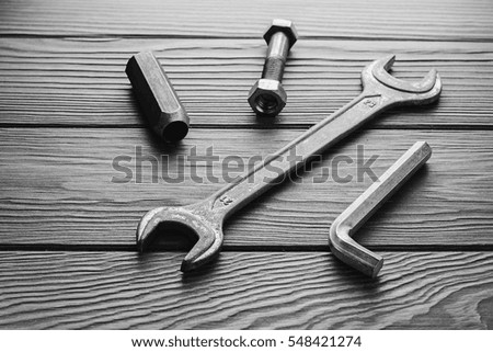 Adjustable wrenches, spanners on wooden texture. Black and white picture.