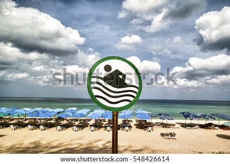 By the empty beach sand benches swimming sign umbrella blue sky clouds