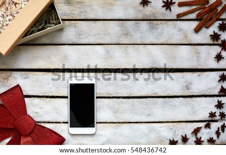 Festive red bow, gift box, smartphone and kitchen herbs on the white wooden table. Holiday and gift concept. picture with free space for text