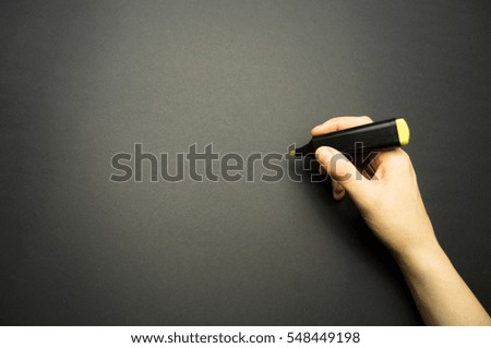 Hand and marker on a black background