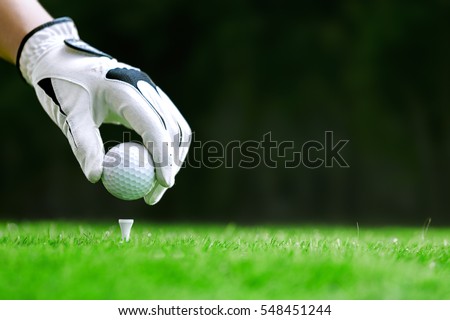 Hand putting golf ball on tee in golf course Royalty-Free Stock Photo #548451244
