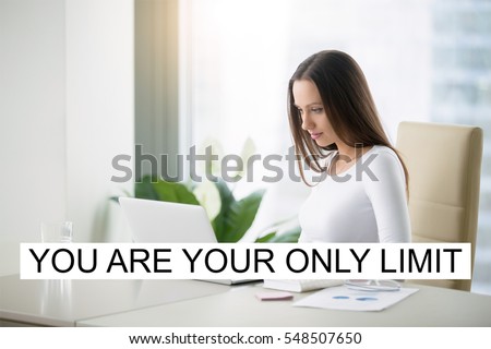 Young woman working at the modern office desk with a laptop. Lady boss at her workplace. Business success concept. Photo with motivational text "You are your only limit"