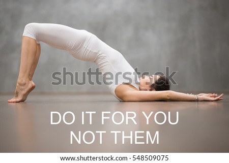 Fit woman with tattoo on foot mean "Wild cat" doing yoga or pilates exercise. Fitness motivation quote with motivational text "Do it for you not them". Healthy lifestyle concept. Shoulder bridge pose