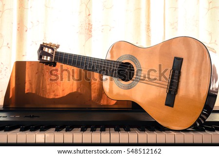 Guitar on piano keyboard. Classical music instrument. Art and abstract background. Warm color tone.