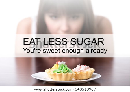 Dieting woman sitting in front of plate with cream tart cakes, looking at forbidden food with unhappy and hungry expression. Photo with motivational text "Eat less sugar. You are sweet enough already"