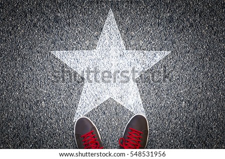Sneakers on asphalt road with white star shape Royalty-Free Stock Photo #548531956
