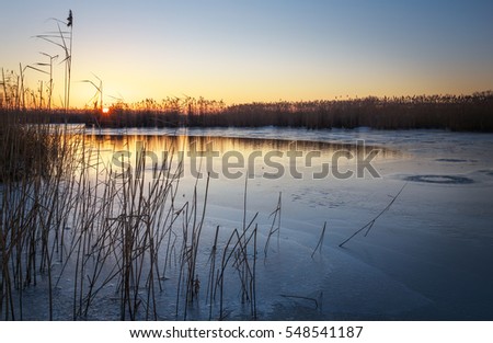 Winter landscape with sunset sky and frozen river. Daybreak

