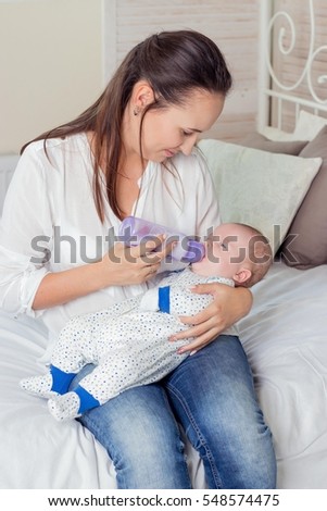 Mother gives the baby a bottle of milk. Baby eats from a bottle.