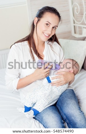 Mother gives the baby a bottle of milk. Baby eats from a bottle.
