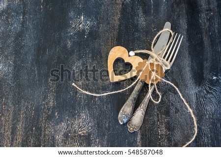 Festive table setting with napkin, vintage silverware and hearts on dark rustic wooden table with copyspace