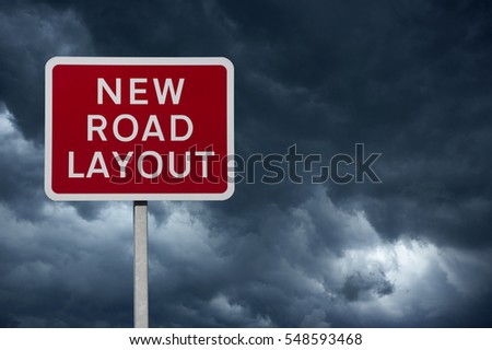 RED NEW ROAD LAYOUT WARNING SIGN WITH BLUE STORMY SKY AND CLOUDS IN BACKGROUND