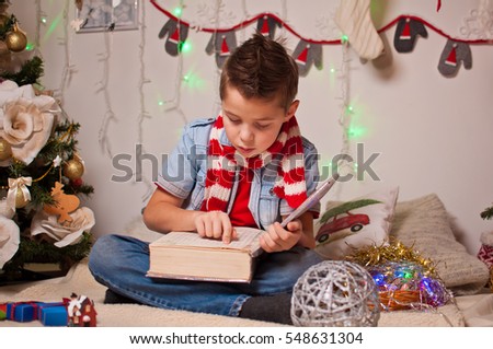 he boy in the striped scarf at the tree reading a book