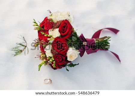 Wedding bouquet of white and red roses on snow.