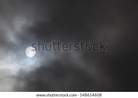 Afternoon Sun Shining Through Dark Clouds - Photograph of an afternoon sun peeking through dark storm clouds as they roll across the sky.  