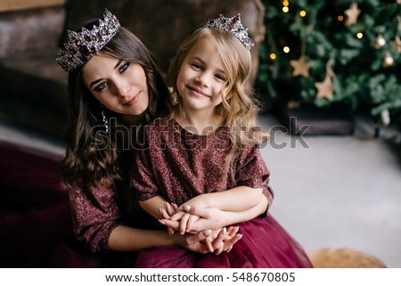 beautiful mother and her daughter in the image of the queen and the princess in the Marsala-colored dress with a long train in the loft