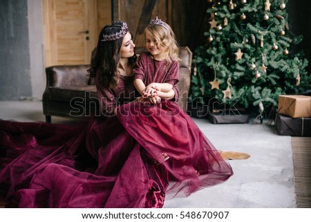 beautiful mother and her daughter in the image of the queen and the princess in the Marsala-colored dress with a long train in the loft