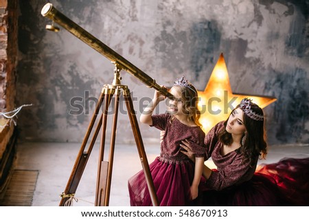 the queen and her daughter Princess looking at the stars through a telescope in the loft