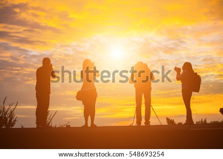 Group of people standing in an open field watching the sunset