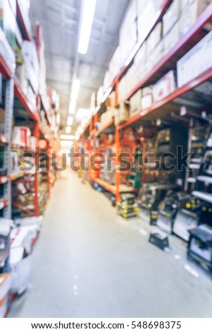 Blurred large hardware store in America. Defocused interior home improvement retailer with rack, aisle of signs, mailboxes, wet/dry vacuums, attic stairs, ladders and building materials. Vintage tone