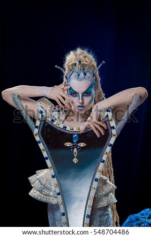 emotional actress woman in makeup and costume elf queen on blue-black background
