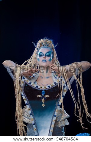 emotional actress woman in makeup and costume elf queen on blue-black background