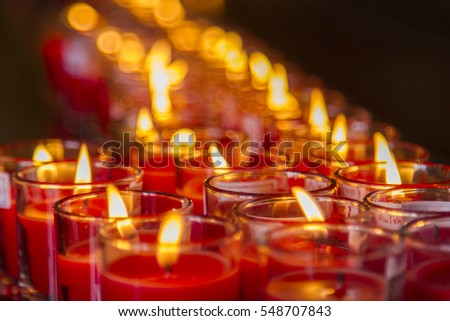 Burning candles in sconces on darkness background.