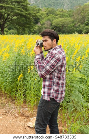 Handsome man take a photo with classic camera,Hipster man take photos in nature ,landscape,macro picture .He is traveler, vintage tone
