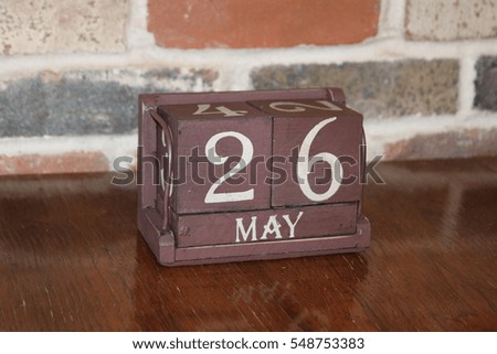 Brown Wooden Calendar Showing the Date of May 26th with Brick Background
