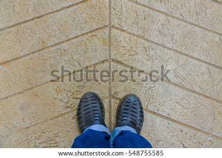 Selfie foot black shoes on concrete pavement, top view.