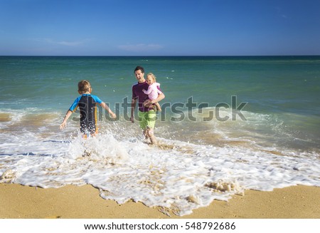 Father with kids playing at the beach in Australia