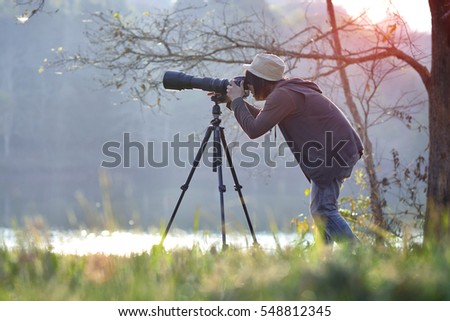 Photographer in action with telephoto lens at morning light