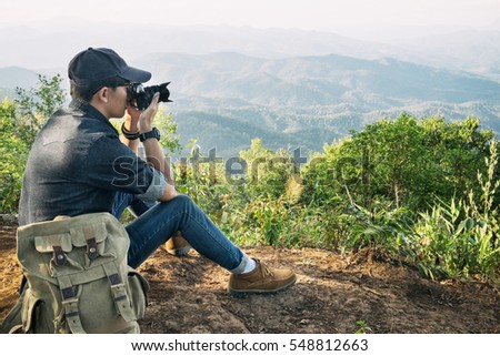 Young professional travrler man with camera shooting outdoor, fantastic mountain landscape.