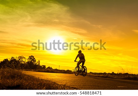 silhouette of the cyclist on road bike at sunset,Silhouette of cyclist in motion on the background of beautiful sunset.