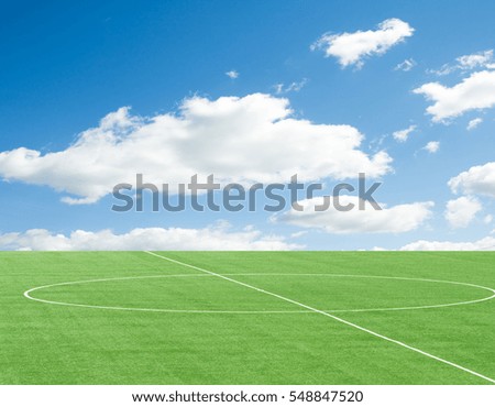 green football field against the sky with clouds
