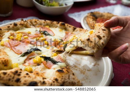 Hand taking out sliced of pizza