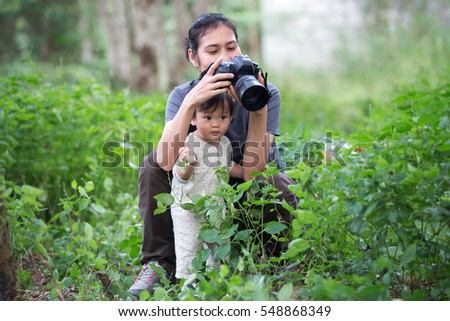 Little baby boy assisting his mother to taking photo, outdoors.