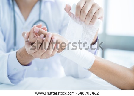 Close-up doctor is bandaging upper limb of patient. Royalty-Free Stock Photo #548905462