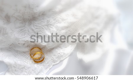 Two golden rings on white lace and satin fabric. Copy space