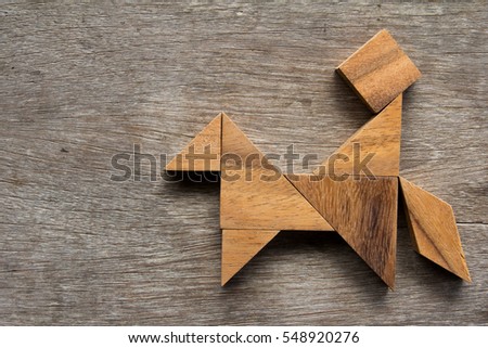 Wooden tangram as man ride the horse shape on old wood background