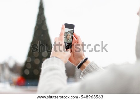 Young man holding a mobile phone and takes pictures himself.