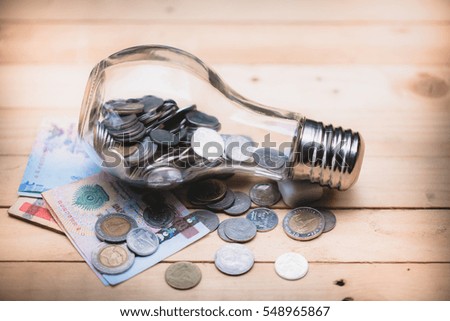 Blurred coin in bulbs jar with wooden board
