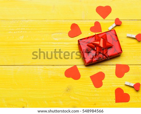 set of colorful decorative valentine hearts, pegs, red present or gift with cute bow on yellow vintage wooden background