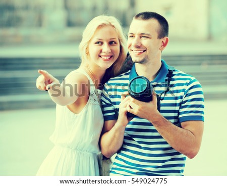 Young glad couple taking picture with camera in town while traveling