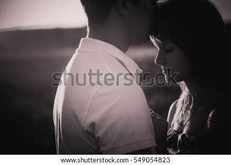 Black white photography romantic couple standing  and kissing on background summer meadow sunset