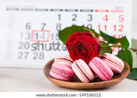 Concept Valentine's Day, red rose and pastries on background on the calendar on data February 14