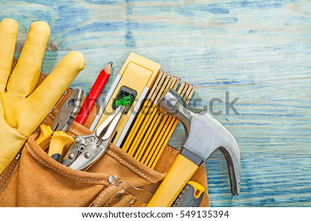 Leather tool belt with construction tooling on wooden board maintenance concept. Royalty-Free Stock Photo #549135394