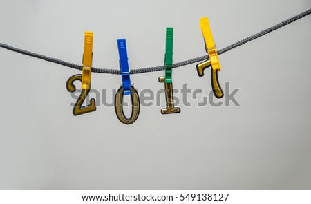 The word 2017 spelled out on colorful plastic clothespin clipped metal golden numbers in front. isolated on white or gray background 